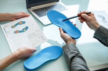 Podiatrist fitting custom orthotics to alleviate foot pain and improve mobility