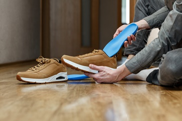 Man Putting Custom Orthotics Into Their Shoes | Experienced Idaho Podiatrist