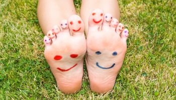 Feet in grass with smiley faces drawn on them | Experienced Idaho Podiatrist
