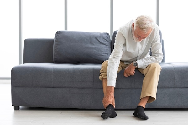 Older-man-on-couch-rubbing-ankle