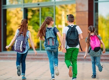 Children walking to school with backpacks for back-to-school foot health awareness