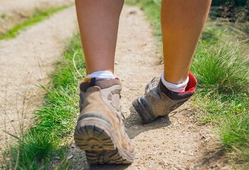 Hiker wearing sturdy boots to help prevent ankle sprains on a trail.