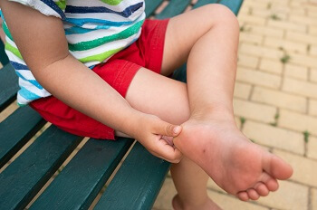 Child holding heel in pain after playing outdoors