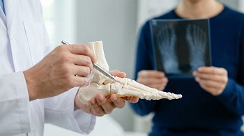 Podiatrist explaining foot pain using a foot model and X-ray
