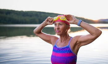 Active older woman swimming in mountain lake