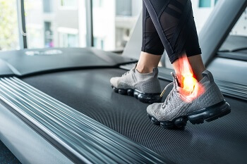 Woman running on a treadmill with ankle brace for injury prevention