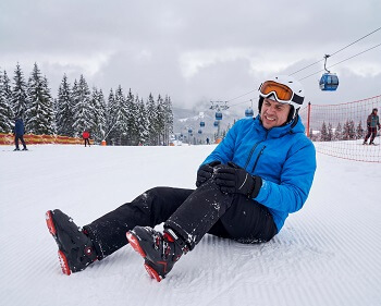 Skier experiencing knee pain while wearing ski boots.
