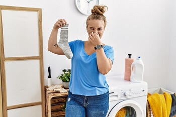 Woman reacting to smelly sock caused by sweaty feet